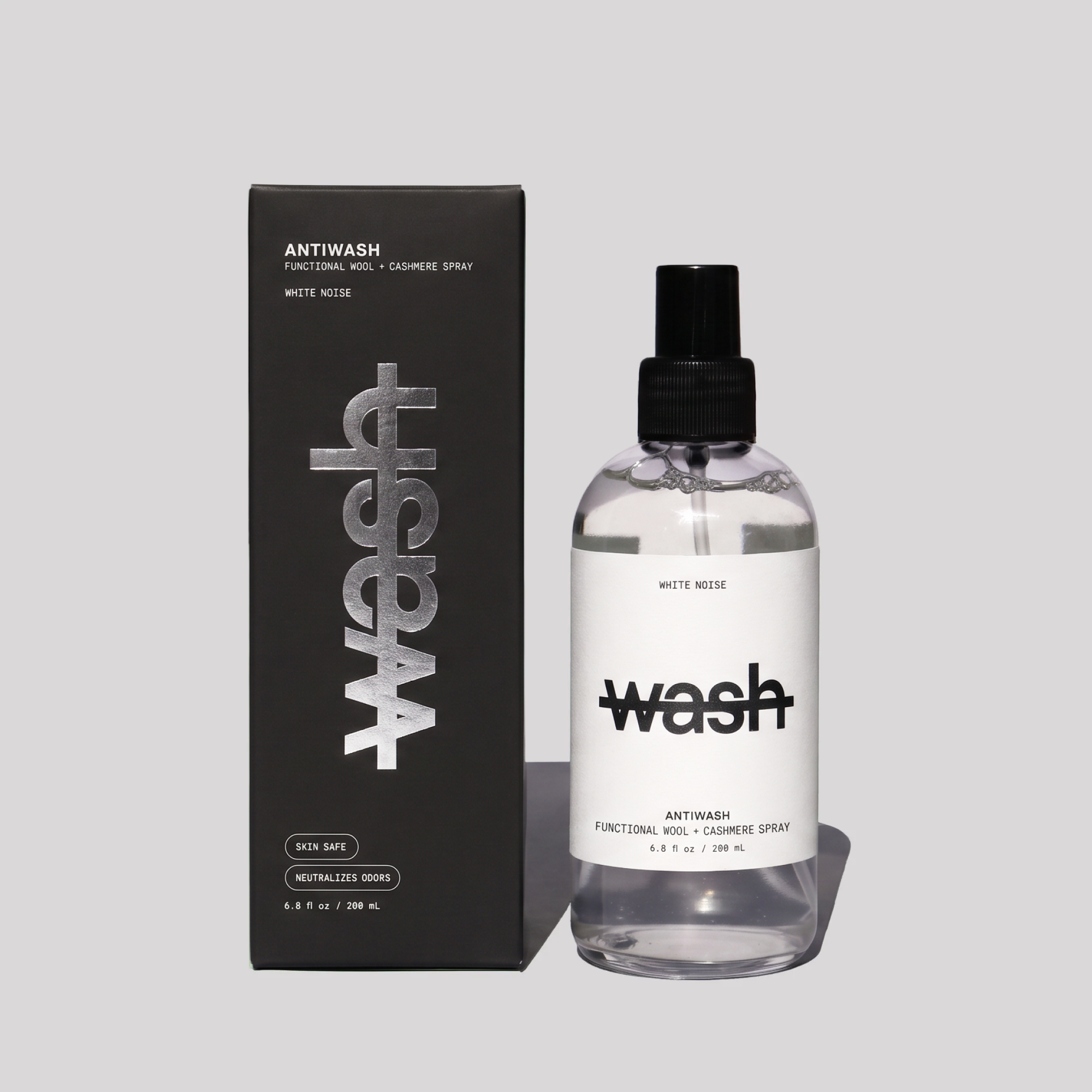 A bottle of White Noise Antiwash Functional Wool + Cashmere Spray next to its black packaging box, set against a solid light gray background.