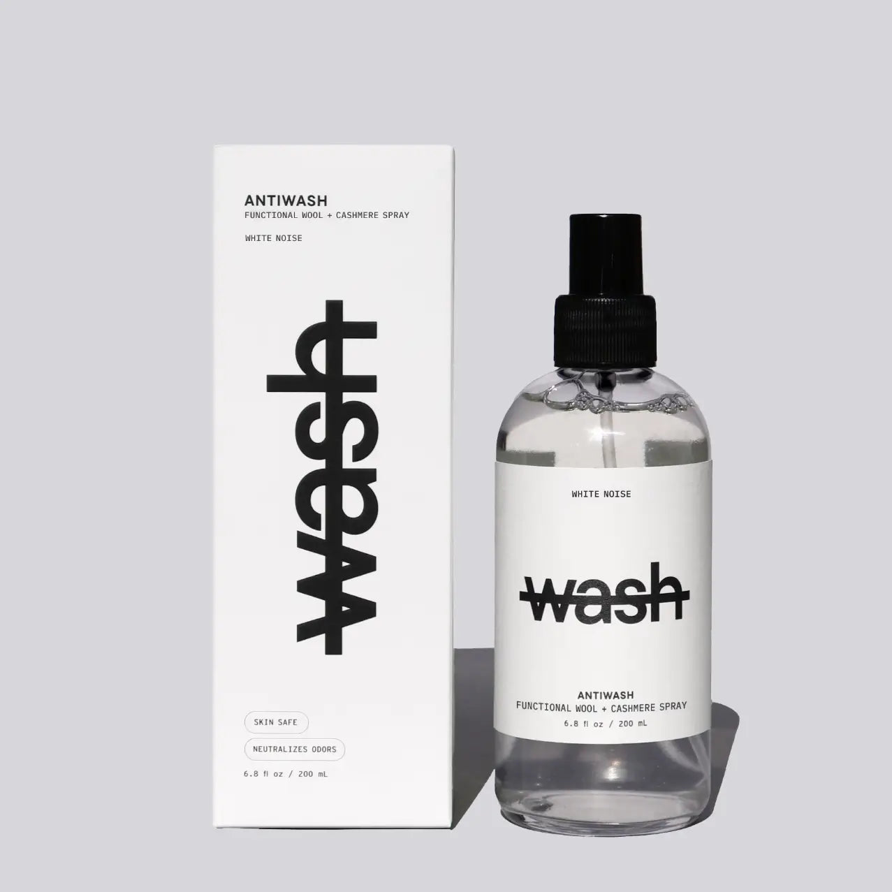 A clear 200 bottle of wash functional wool + cashmere spray with a black spray top and white label, standing next to its white packaging box with bold black text, on a light gray background.