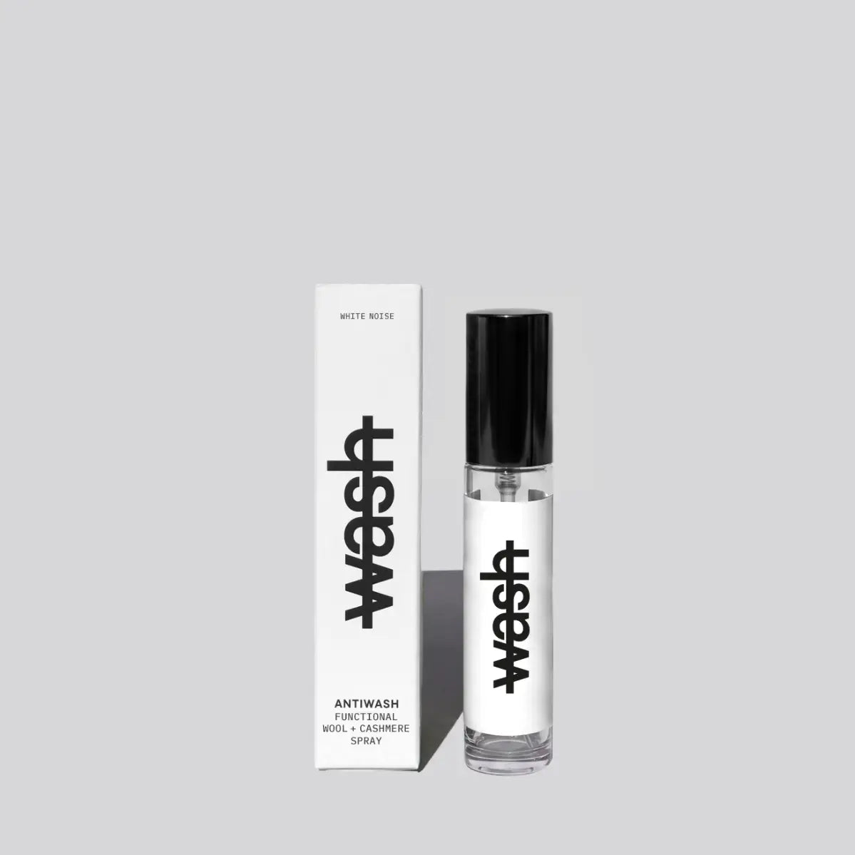 A clear 15ml bottle of Antiwash Functional Wool + Cashmere Spray with a black cap stands next to its white packaging box, both featuring the brand name 'wash' in black text, on a solid light gray background.